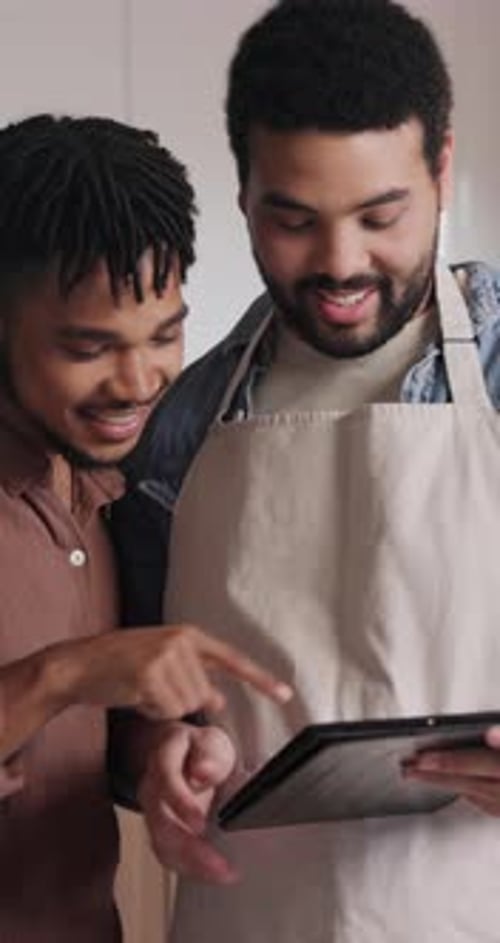 Two People Smiling at Tablet in Kitchen