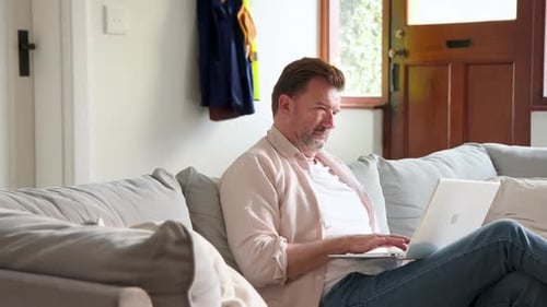 Man Working on Laptop While Relaxing on Sofa