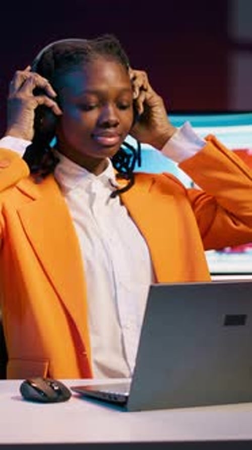 Smiling Young Woman Works at Laptop with Headphones