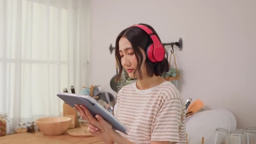 Woman Using Tablet in Kitchen with Headphones
