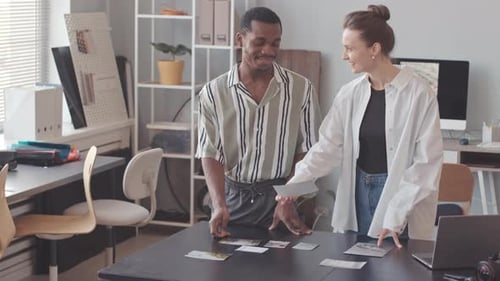 Multiethnic Couple of Photographers Examining Printed Photos in Studio