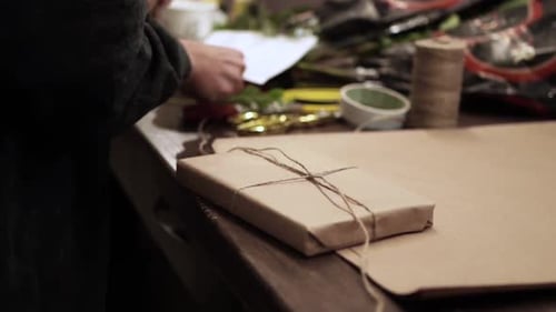 Adult Wrapping a Gift with Brown Paper and Twine