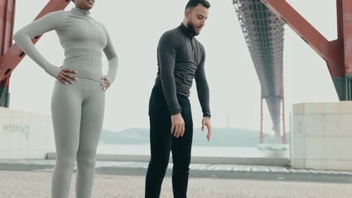 Couple Doing Warm Up Exercises Outdoors By a Bridge