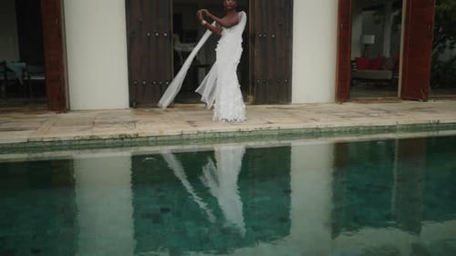 Nonbinary Black Person Model Poses in White Dress at Luxury Villa Entrance By Swimming Pool Gay