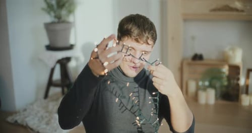 Young Man Untangling Christmas Lights Indoors