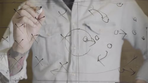 Hand Drawing a Soccer Strategy Plan on a Glass Screen