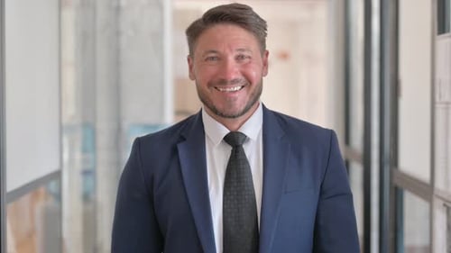 Porträt eines lächelnden Geschäftsmannes mittleren Alters, der in die Kamera schaut