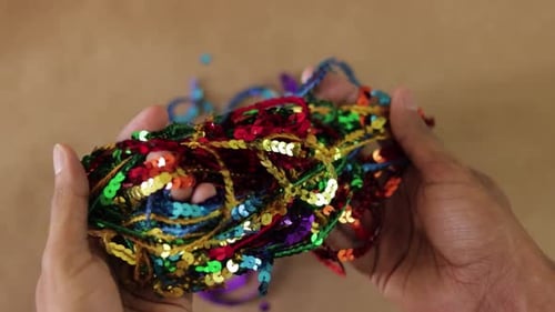 Bandes de paillettes de nombreuses couleurs vives. Mains brunes. Fournitures d'artisanat.