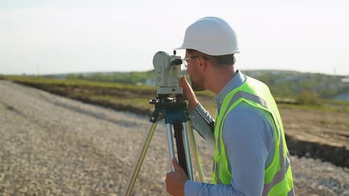 Surveyor Using Theodolite for Road Construction on Bright Day