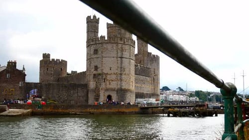 Historic Caernarfon castle Welsh medieval harbour waterfront town landmark dolly left through railin