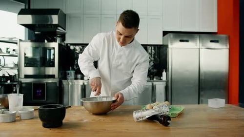 Young Man Mixing Ingredients in Kitchen with Whisk
