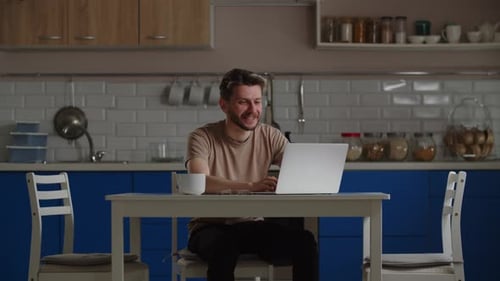 Man Working at Laptop in a Kitchen