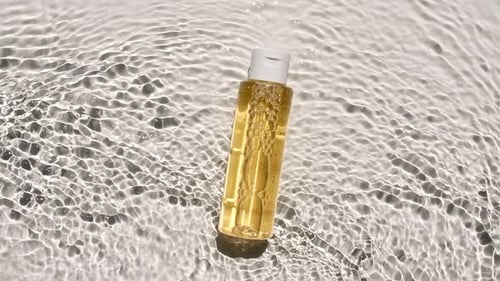 Golden Liquid in Clear Bottle Under Rippling Water