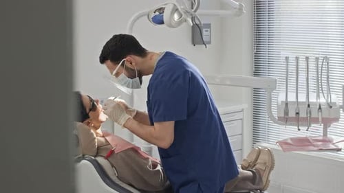 Dentist Checking Patient Teeth Using Tools on Treatment Chair in Clinic