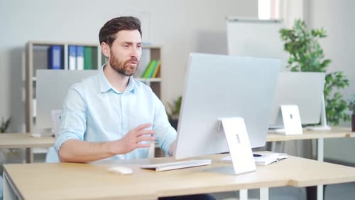 Man Teleconferencing at Computer in Bright Modern Office
