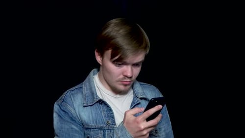 Young Man Using Smartphone on Black Background