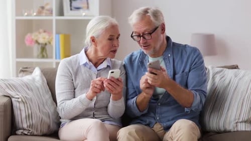Smiling Senior Couple Using Smartphones Together at Home