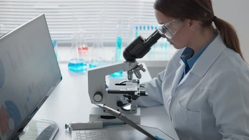 Female Scientist Analyzes Data with Microscope in Lab