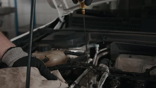 Anonymer Automechaniker entfernt Ölmessstab, um den Ölstand zu überprüfen