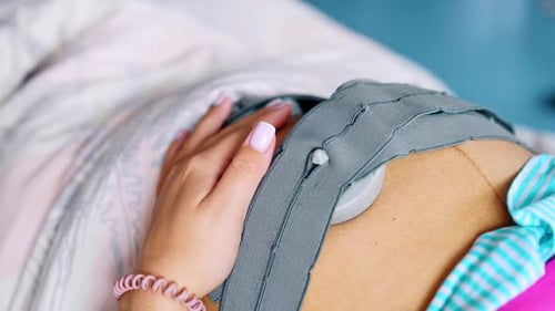 Une femme inconnue caresse son gros ventre avec une ceinture foetale pour CTG.