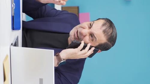 Confused Business Man Working at Desk on Phone