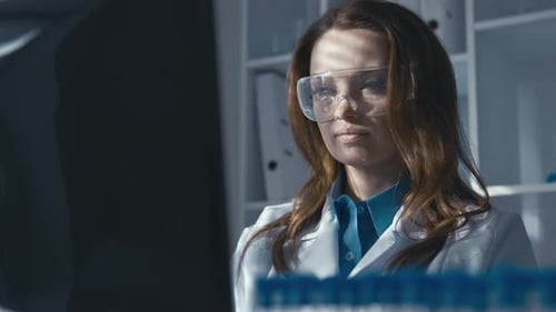 A Scientist in Protective Chemical Glasses Works at a Computer Monitor Laboratory for Research and