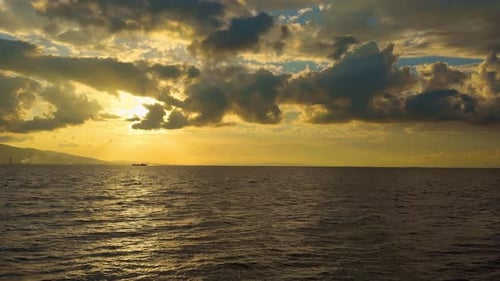 Orange Cloudy Sunset With Ocean And Cargo Ship On The Horizon