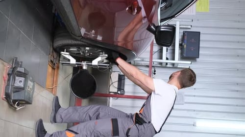 Vertikales Video eines Mechanikers, der das Chassis auf Beschädigungen oder Verschleiß überprüft