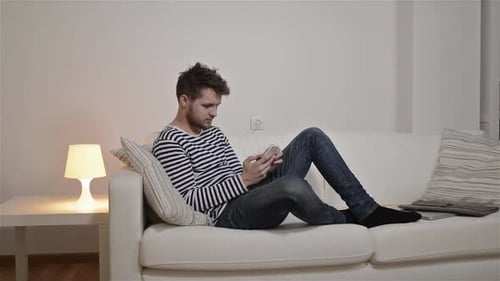 Man relaxing on couch while using mobile device