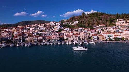 Catamaran Yacht cruising past a boat village in Greece. Aerial tracking shot