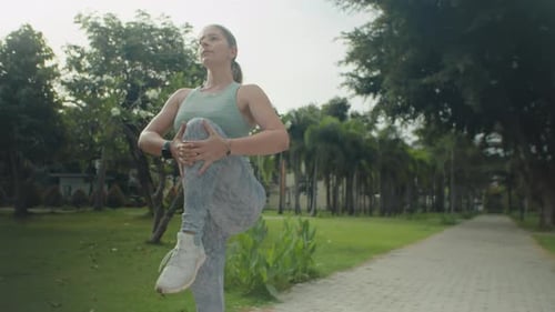 Athletic Woman Stretching Legs before Run in Park