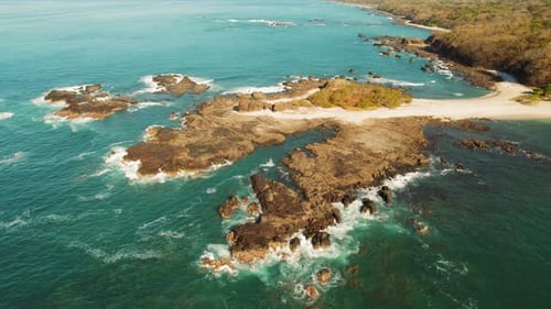 Scenic aerial view of rocky island coastline with waves breaking along the shore