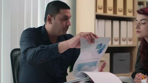 Entrepreneurs Talking about Business Charts at Office