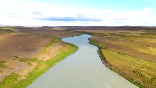 Aerial establishing shot of a large river running through the Icelandic countryside