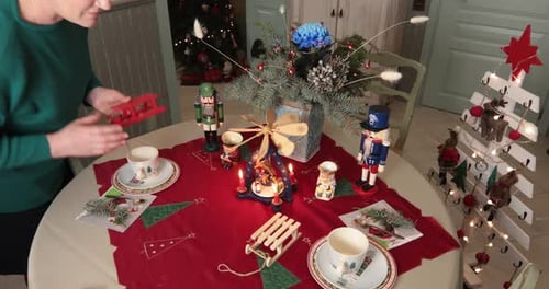 Woman Arranging Christmas Table with Festive Decorations