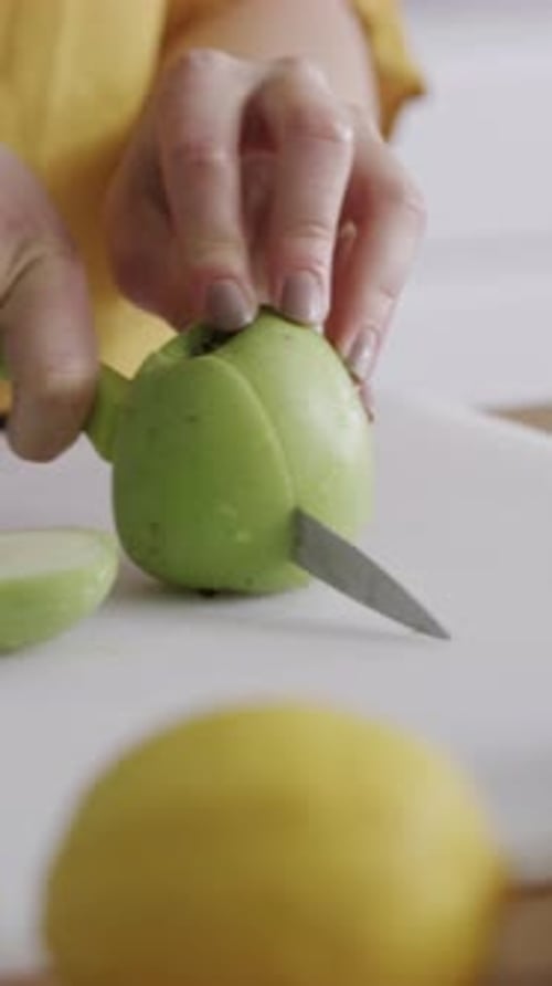 Woman cuts green apple on cutting board indoors