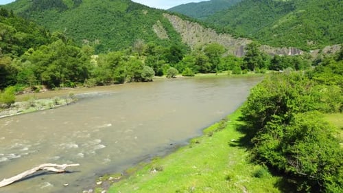 Fluss fließt durch ein grünes Tal mit Bergen