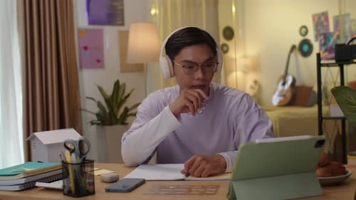 Young Adult Studies Indoors with Tablet and Notebook