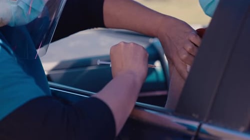 Nurse giving shot of covid vaccine in shoulder, drive through, close up, New Zealand