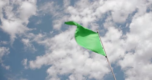 Green Flag Waving Against Blue Sky