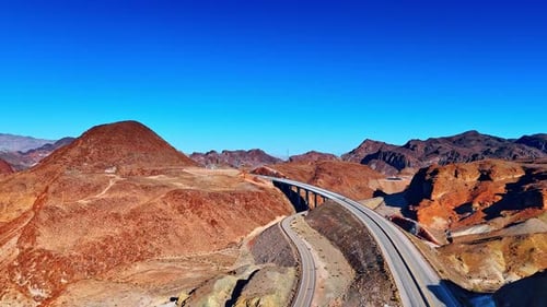 Cars ride by the road and bridge over the gulch in the rocks.