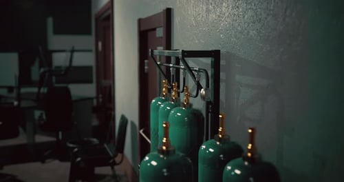 Sturdy Green Gas Cylinders Lined Up Against the Wall in a Dimly Lit Room