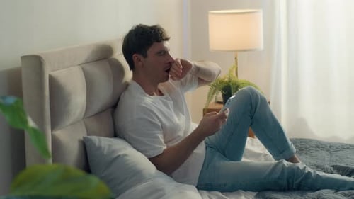 Caucasian Man Lying on Bed Bedroom Home Comfortable Cozy Yawning Laziness Male Bored Sleepy Holding