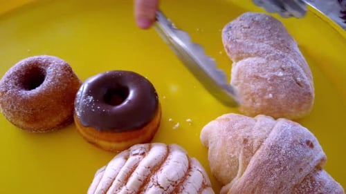 Hand selecting pastry from bakery tray