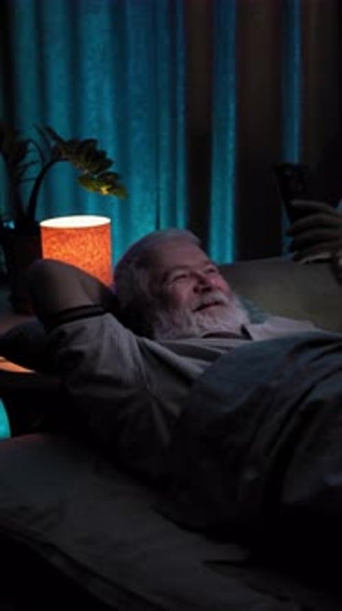 Unable to Sleep the Man Lies in Bed and Watches the Content on His Mobile Phone