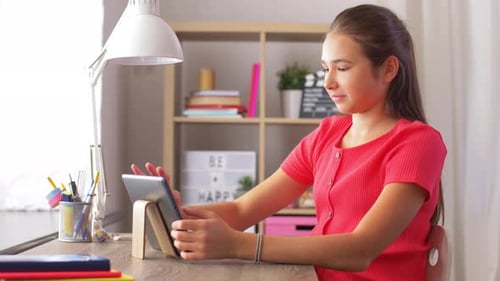 Teen girl using tablet computer at desk