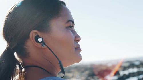 Woman Wearing Earbuds Outdoors on Sunny Day Close Up