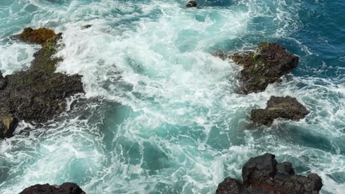 Waves create turbulent water with abstract textures, with white foams