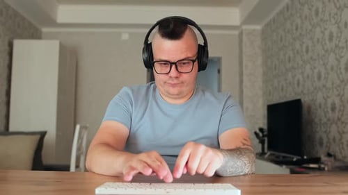 Man Typing on Computer Keyboard with Headphones