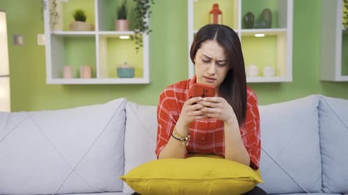 Woman Using Phone Looks Upset on Couch